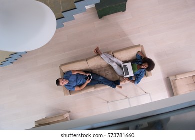 Young Multiethnic Couple Relaxes In The Luxury Living Room, Using A Tablet And Laptop Computer Top View