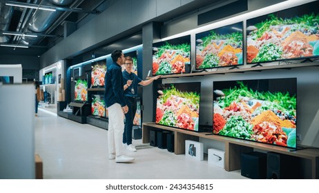 Young Multiethnic Customer Advising with Retail Home Electronics Store Salesperson. Stylish Man is Interested in Buying a Flat-Screen TV. Client Shopping for a New Television Set in Modern Shop - Powered by Shutterstock