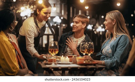 Young Multiethnic Friends Enjoying a Night Out in a Cafe. Waiter Bringing a Delicious Italian Pizza. Young Men and Women Having Fun Conversations on a Terrace, Enjoying Tasty Food and Beverages - Powered by Shutterstock