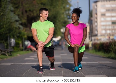 Young Multiethnic Jogging Couple Warming Up And Stretching Before Morning Running In The City