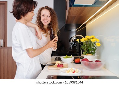 Young Multi-ethnic Lesbian Couple Drinking Beer And Cooking Dinner Together