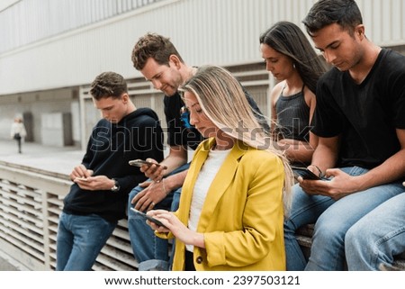 Young multiethnic male and female students using smartphone on street