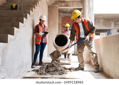 Young multiethnic masons mixing cement by supervisor - Powered by Shutterstock