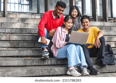 Young multiethnic students reading, studying on laptop, preparing for exam or working on group project while sitting on staircase or steps of college campus  - Shutterstock ID 2311788283
