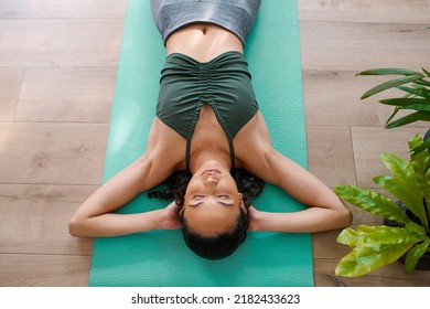 A Young Multi-ethnic Woman Rests On Her Yoga Mat With Eyes Closed Laying Down