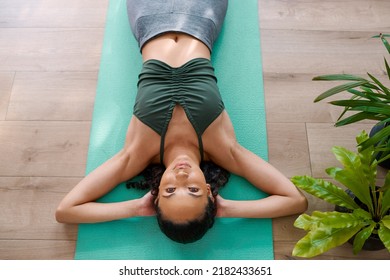 A Young Multi-ethnic Woman Rests On Her Yoga Mat Laying Down