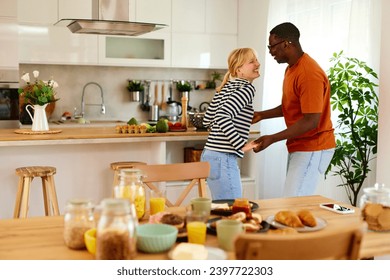 Young multiracial couple dancing in the kitchen in the morning - Powered by Shutterstock