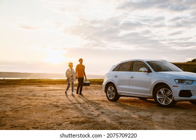 Young multiracial couple going with cooler bag to their car outdoors - Powered by Shutterstock