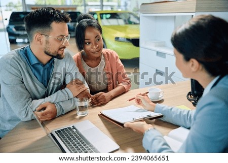Young multiracial couple going through paperwork with saleswoman during a meeting in showroom. 