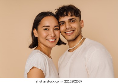 Jóvenes parejas multirraciales posando mientras sonríen juntos aislados sobre un fondo beige