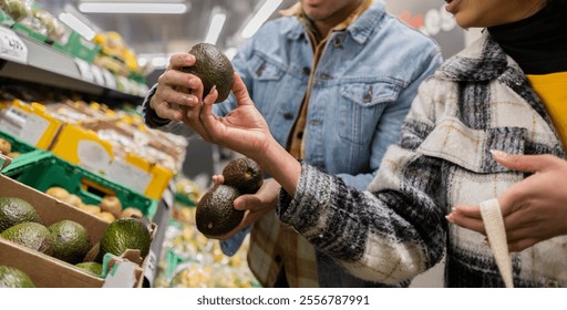 Young multiracial couple selecting ripe avocados in the supermarket on valentine's day, enjoying the process of choosing fresh, healthy ingredients for a romantic dinner together - Powered by Shutterstock