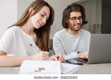 Young multiracial couple smiling while working with laptop together at home