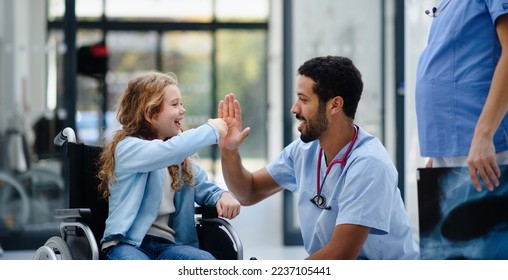 Young multiracial doctor having fun with little girl on wheelchair. - Powered by Shutterstock