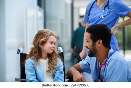 Young multiracial doctor talking with little girl on wheelchair. - Powered by Shutterstock