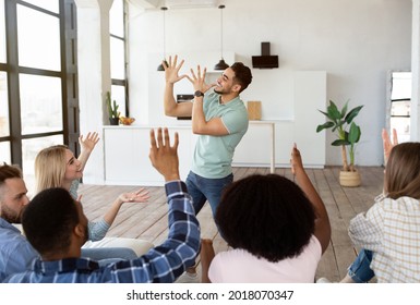 Young multiracial friends playing charades game at home. Arab guy showing pantomime riddles, his fellow students trying to guess during student party. Fun domestic entertainments concept