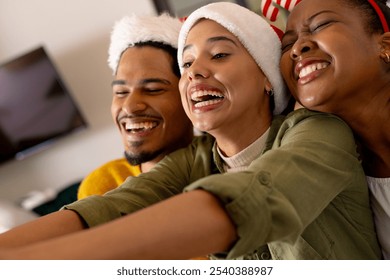 Young multiracial friends wearing Santa hats laughing and taking selfie at Christmas party, at home. Holiday, celebration, festive, joy, happiness, winter - Powered by Shutterstock