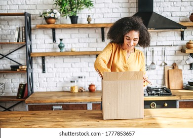 A young multi-racial girl received an online delivery order. Attractive woman with Afro hairstyle unpack the box in the kitchen