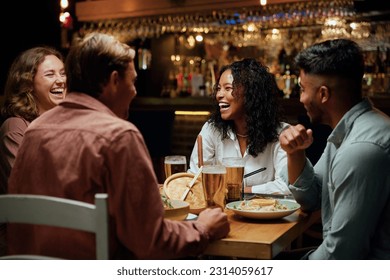 Young multiracial group of friends in casual clothing laughing around table with food and drinks - Powered by Shutterstock