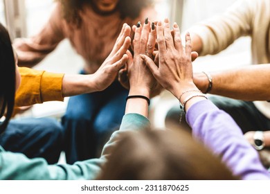 Young multiracial group stacking hands together- Happy diverse friends united at community table having fun- youth Millennial students giving strength motivation- Human resources teamwork concept