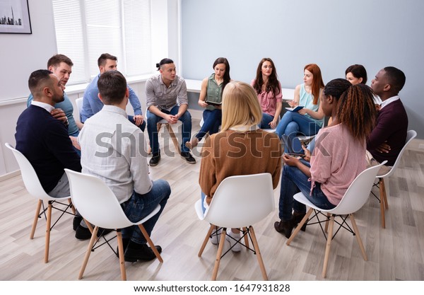 Young Multiracial Millennial Friends Sitting\
In Circle Having Group\
Discussion