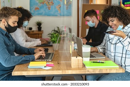 Young multiracial people using computer in co-working creative space while wearing face mask - Health and business technology concept - Powered by Shutterstock