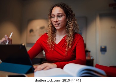 Young multiracial professional using stylus on tablet screen for digital planning, talented woman student multitasking with textbook and gadget in cafe, IT and software development concept.
