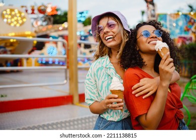 Young multiracial women eating ice cream while spending time in attraction park - Powered by Shutterstock