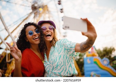 Young multiracial women taking selfie on cellphone while spending time in attraction park - Powered by Shutterstock