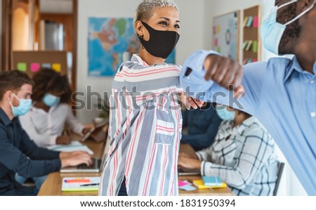 Young multiracial workers wearing face mask doing new social distance greetings bumping elbows inside co-working creative space 