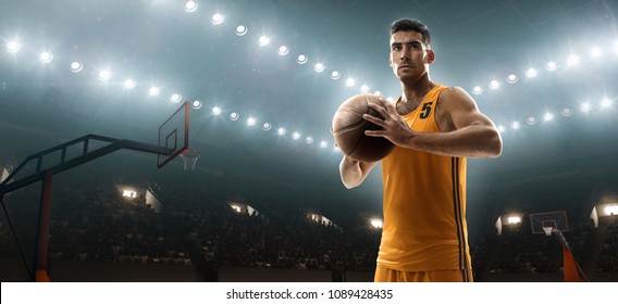 Young muscular basketball player holding a ball on floodlight professional basketbal court - Powered by Shutterstock