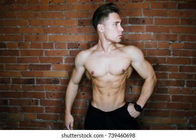 Young Muscular Bodybuilder Fitness Model Posing Against A Brick Wall Loft Fitness Club. Beauty Ring Flash, Fashion Potrait. Six Pack Abs.