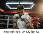 Young muscular boxer in boxing gloves looking at camera.