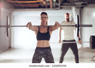 Young Muscular Couple Doing Power Clean Exercise With Barbell On Hard Training At The Garage Gym.