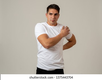 Young muscular fitness man touching and grabbing his lower back suffering strong pain isolated on neutral background. In sport injury Incorrect posture problems and body health care.
