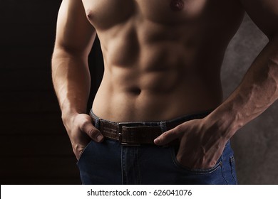 Young muscular male athlete demonstrates his torso, relief abdominal muscles