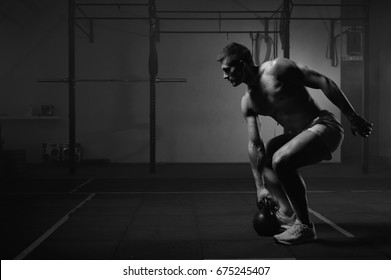 Young Muscular Man Doing Exercises With Kettlebell In Gym. Weightlifting Workout. Sports, Fitness Concept. Black And White Image.