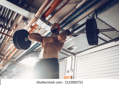 Young Muscular Man Doing Power Clean Exercise With Barbell On Hard Training At The Garage Gym.