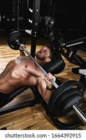 Young Muscular Man Lifting A Barbell Bench Press In The Gym. Beautiful Body, Goal Achievement, Sport As A Way Of Life.