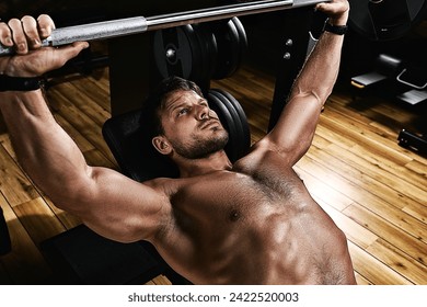 Young muscular man lifting a barbell bench press in the gym. Beautiful body, goal achievement, Sport as a way of life.
