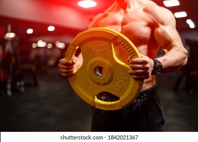 Young Muscular Man Lifting Weights Over Dark Gym Background. Full Length Portrait. Selective Focus.