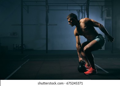 Young Muscular Man With Naked Torso Working Out In Gym. Athletic Male Adult Exercising With Kettle Bell. Fitness, Sports Concept.