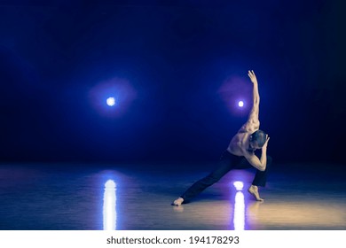 Young And Muscular Man Performing A Contemporary Dance Pose On A Stage.