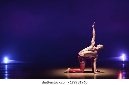 Young And Muscular Man Performing A Contemporary Dance Pose On A Stage.