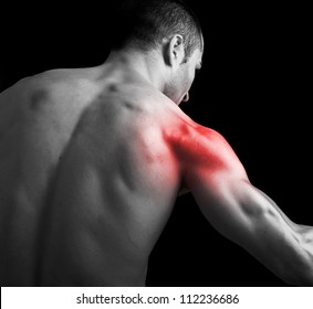 Young muscular man with shoulder pain on black background