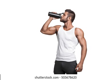 Young Muscular Man Showing His Perfect Body. Isolated. 
A Man Drinking From A Cocktail Shaker With The Protein