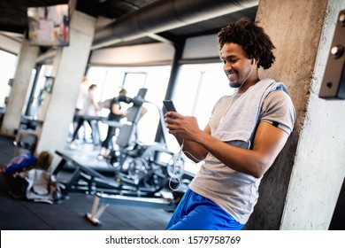 Young Muscular Man Using Mobile Phone At The Gym In Exercise Break