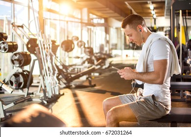 Young Muscular Man Using Mobile Phone At The Gym.