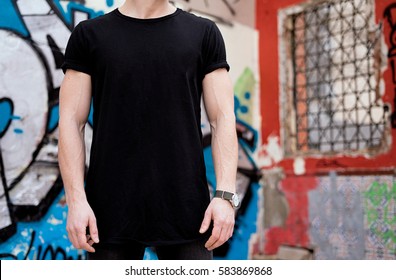 Young Muscular Man Wearing Black Tshirt And Jeans Posing In Modern District.Blurred Graffiti On The Background. Hotizontal Mockup