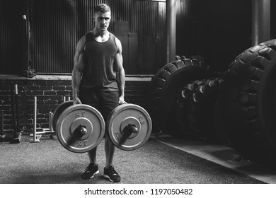 Young muscular sportsman doing farmer's walk exercise during his training workout