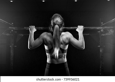 Young muscular woman doing pull up exercise on horizontal bar. Fit female practicing strength training. Fitness, sports concept. - Powered by Shutterstock